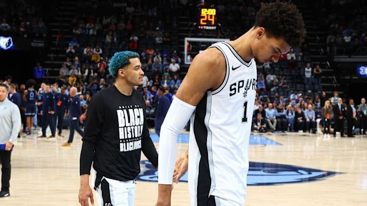 Feb 3, 2025; Memphis, Tennessee, USA; San Antonio Spurs forward Jeremy Sochan (10) and San Antonio Spurs center Victor Wembanyama (1) walk off the court after a delayed start to the game, as medical personnel check on a fan before the game against the Memphis Grizzlies at FedExForum. Mandatory Credit: Petre Thomas-Imagn Images
