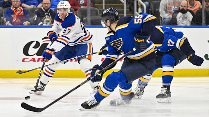 Feb 4, 2025; St. Louis, Missouri, USA;  Edmonton Oilers center Connor McDavid (97) passes the puck as St. Louis Blues defenseman Colton Parayko (55) defends during the first period at Enterprise Center. Mandatory Credit: Jeff Curry-Imagn Images