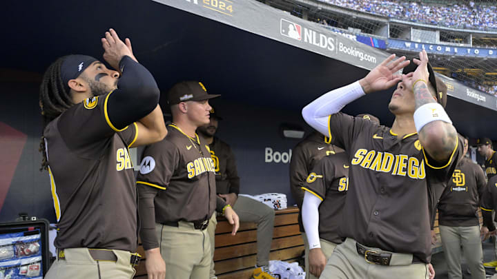 Oct 11, 2024; Los Angeles, California, USA; San Diego Padres outfielder Fernando Tatis Jr. (23) and San Diego Padres third baseman Manny Machado (13) react in the dugout before game five against the Los Angeles Dodgers in the NLDS for the 2024 MLB Playoffs at Dodger Stadium. Mandatory Credit: Jayne Kamin-Oncea-Imagn Images