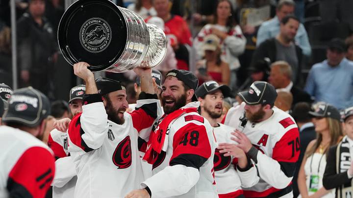Jun 14, 2026; Las Vegas, Nevada, USA; Carolina Hurricanes left wing Jordan Martinook (48) hands the the Stanley Cup to defenseman Shayne Gostisbehere (4) after defeating the Vegas Golden Knights in game six of the 2026 Stanley Cup Final at T-Mobile Arena. Mandatory Credit: Stephen R. Sylvanie-Imagn Images