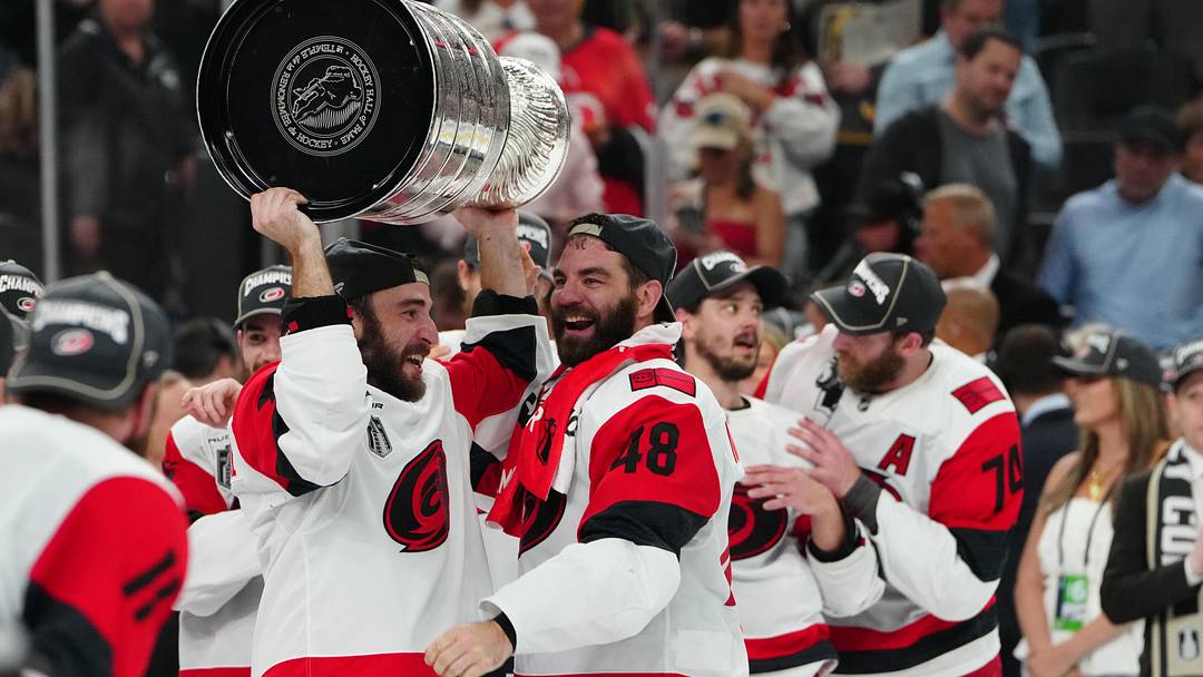Jun 14, 2026; Las Vegas, Nevada, USA; Carolina Hurricanes left wing Jordan Martinook (48) hands the the Stanley Cup to defenseman Shayne Gostisbehere (4) after defeating the Vegas Golden Knights in game six of the 2026 Stanley Cup Final at T-Mobile Arena. Mandatory Credit: Stephen R. Sylvanie-Imagn Images