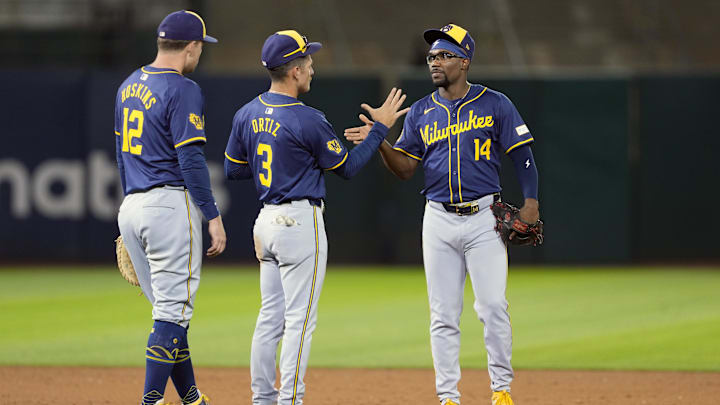 Aug 23, 2024; Oakland, California, USA; Milwaukee Brewers second baseman Andruw Monasterio (14) celebrates with third baseman Joey Ortiz (3) and first baseman Rhys Hoskins (12) after defeating the Oakland Athletics at Oakland-Alameda County Coliseum. Mandatory Credit: Darren Yamashita-Imagn Images