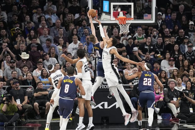 San Antonio Spurs forward Victor Wembanyama (1) blocks a shot attempted by Denver Nuggets forward Christian Braun (0).