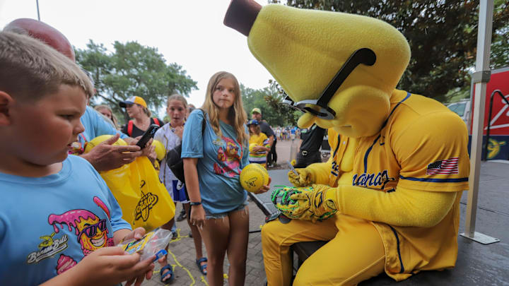 Savannah Bananas mascot Split signs a glove during the opening ceremony for the Banana Ball Youth Tournament on Wednesday, July 9, 2025 at Historic Grayson Stadium in Savannah. Savannah Bananas mascot Split signs a glove during the opening ceremony for the Banana Ball Youth Tournament on Wednesday, July 9, 2025 at Historic Grayson Stadium in Savannah.