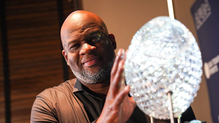 Oct 18, 2024; Austin, TX, USA; Vince Young stands with the AFCA Coaches’ Trophy at Vince Young Steakhouse. The trophy is presented by US LBM and awarded to the national champion and number one team in the US LBM coaches poll. Young played for the Texas Longhorns and helped the team bring home the trophy at the end of the 2005 season. Texas is currently ranked No. 1 in the latest poll. Mandatory Credit: Dustin Safranek-Imagn Images