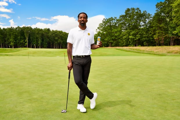 J.R. Smith holds a seltzer can on a golf course.