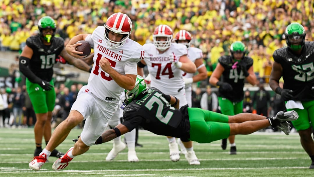 Oct 11, 2025; Eugene, Oregon, USA; Indiana Hoosiers quarterback Fernando Mendoza (15) runs with the ball against  a diving tackle attempt by Oregon Ducks defensive back Aaron Flowers (21) during the first quarter at Autzen Stadium. Mandatory Credit: Troy Wayrynen-Imagn Images