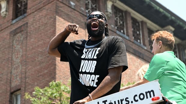 Boston Celtics star Jaylen Brown hypes up the crowd by flexing for them during the team's 2024 NBA championship parade.