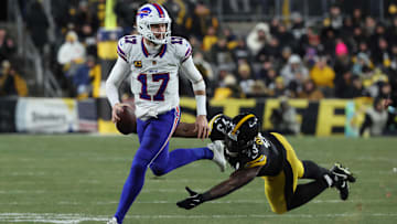 Buffalo Bills quarterback Josh Allen looks to pass as Pittsburgh Steelers defensive end Esezi Otomewo attempts to tackle.