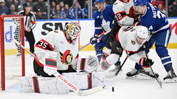 Mar 15, 2025; Toronto, Ontario, CAN;  Ottawa Senators goalie Linus Ullmark (35) makes a save as defensemen Artem Zub (2) and Thomas Chabot (72) hold back Toronto Maple Leafs forward Auston Matthews (34) in the third period at Scotiabank Arena. Mandatory Credit: Dan Hamilton-Imagn Images