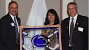 Joe Battista, then Penn State's associate athletic director for hockey, presents a gift to Terry and Kim Pegula in 2010 following their gift for Penn State hockey and Pegula Ice Arena. 