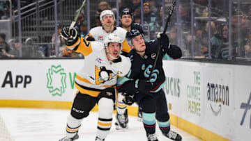 Jan 25, 2025; Seattle, Washington, USA; Pittsburgh Penguins center Sidney Crosby (87) and Seattle Kraken defenseman Ryker Evans (41) chase a loose puck during the second period at Climate Pledge Arena. Mandatory Credit: Steven Bisig-Imagn Images