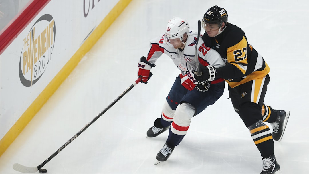 Apr 17, 2025; Pittsburgh, Pennsylvania, USA;  Washington Capitals center Lars Eller (20) over the puck against Pittsburgh Penguins defenseman Ryan Graves (27) during the third period at PPG Paints Arena. Mandatory Credit: Charles LeClaire-Imagn Images