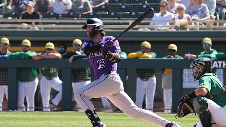 Mar 6, 2026; Mesa, Arizona, USA; Colorado Rockies third baseman Kyle Karros (12) hits a single against the Athletics in the first inning at Hohokam Stadium. Mandatory Credit: Rick Scuteri-Imagn Images