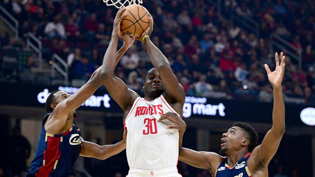 Nov 19, 2025; Cleveland, Ohio, USA; Houston Rockets center Clint Capela (30) looks to pass while being pressured by Cleveland Cavaliers centers Thomas Bryant (3) and Evan Mobley (4) during the first half at Rocket Arena. Mandatory Credit: David Dermer-Imagn Images