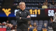 Dec 9, 2025; Morgantown, West Virginia, USA; West Virginia Mountaineers head coach Ross Hodge smiles along the sideline during the second half against the Little Rock Trojans at Hope Coliseum. Mandatory Credit: Ben Queen-Imagn Images
