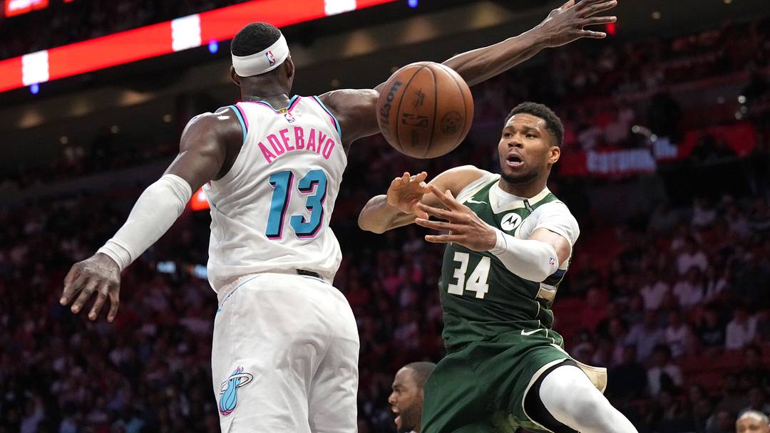 Apr 5, 2025; Miami, Florida, USA;  Milwaukee Bucks forward Giannis Antetokounmpo (34) passes the ball under the arm of Miami Heat center Bam Adebayo (13) during overtime at Kaseya Center. Mandatory Credit: Jim Rassol-Imagn Images
