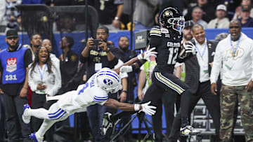 Dec 28, 2024; San Antonio, TX, USA; Colorado Buffaloes wide receiver Travis Hunter (12) runs with the ball as Brigham Young Cougars cornerback Mory Bamba (4) attempts to make a tackle during the second quarter at Alamodome. Mandatory Credit: Troy Taormina-Imagn Images