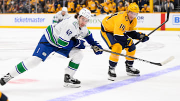 Jan 29, 2025; Nashville, Tennessee, USA;   Vancouver Canucks defenseman Quinn Hughes (43) and Nashville Predators center Gustav Nyquist (14) chase after the puck during the first period at Bridgestone Arena. Mandatory Credit: Steve Roberts-Imagn Images