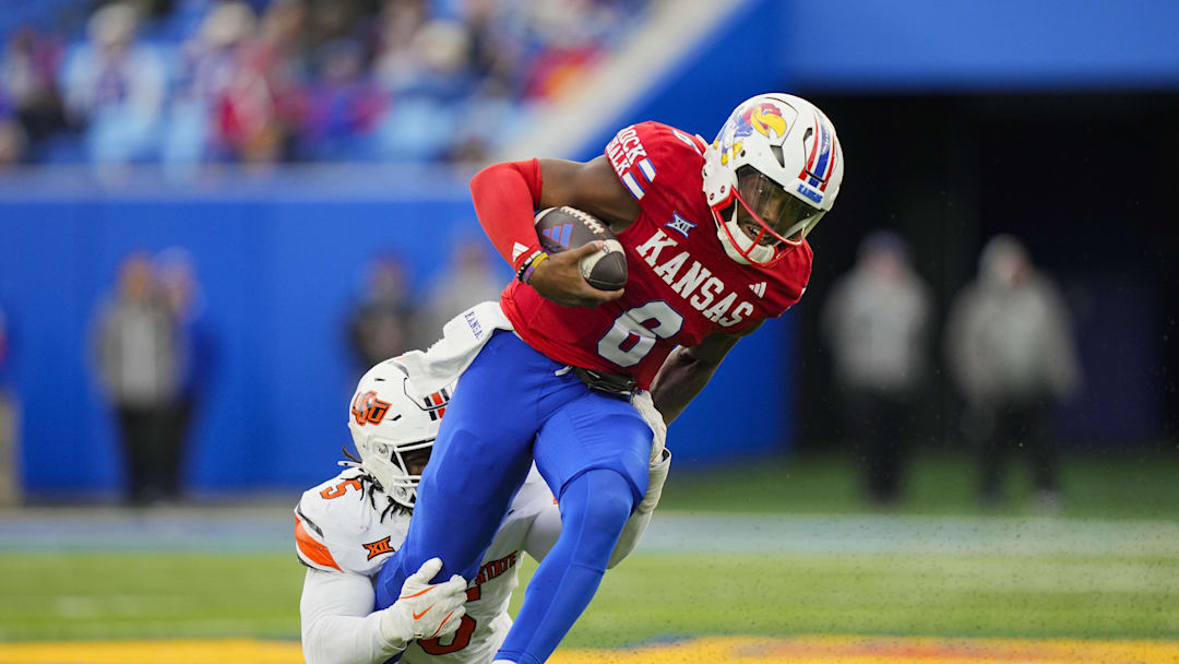 Nov 1, 2025; Lawrence, Kansas, USA; Kansas Jayhawks quarterback Jalon Daniels (6) runs the ball against Oklahoma State Cowboys linebacker Bryan McCoy Jr. (5) during the second half at David Booth Kansas Memorial Stadium. Mandatory Credit: Jay Biggerstaff-Imagn Images