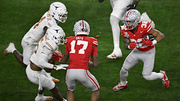 Jan 10, 2025; Arlington, Texas, USA; Ohio State Buckeyes running back TreVeyon Henderson (32) runs against Texas Longhorns defensive back Andrew Mukuba (4) and defensive back Malik Muhammad (5) as Buckeyes wide receiver Carnell Tate (17) blocks during the second quarter of the College Football Playoff semifinal in the Cotton Bowl at AT&T Stadium. Mandatory Credit: Jerome Miron-Imagn Images