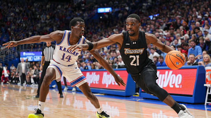 Dec 16, 2025; Lawrence, Kansas, USA; Towson Tigers guard Jack Doumbia Jr. (21) drives against Kansas Jayhawks guard Melvin Council Jr. (14) during the first half at Allen Fieldhouse. Mandatory Credit: Jay Biggerstaff-Imagn Images