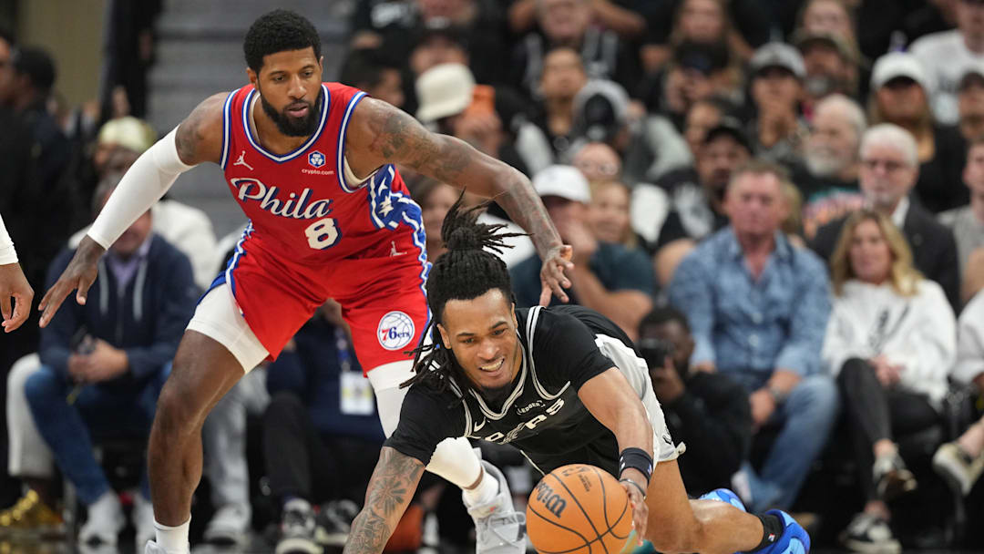 Apr 6, 2026; San Antonio, Texas, USA; San Antonio Spurs guard Stephon Castle (5) reaches for a loose ball ahead of Philadelphia 76ers forward Paul George (8) during the second half at Frost Bank Center. Mandatory Credit: Scott Wachter-Imagn Images