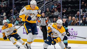 Nov 20, 2024; Seattle, Washington, USA;  Nashville Predators forward Tommy Novak (82) skates with the puck as forward Juuso Parssinen (13) jumps during the third period against the Seattle Kraken at Climate Pledge Arena. Mandatory Credit: Stephen Brashear-Imagn Images