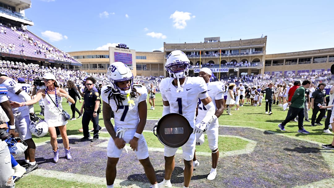 Sep 20, 2025; Fort Worth, Texas, USA; TCU Horned Frogs wide receiver Jordan Dwyer (7) and safety Austin Jordan (1) and celebrate with the Iron Skillet trophy after the Frogs defeat the SMU Mustangs at Amon G. Carter Stadium. Mandatory Credit: Jerome Miron-Imagn Images