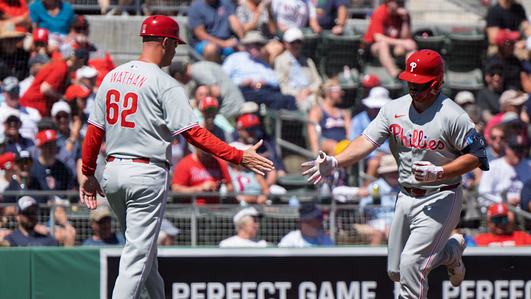 Mar 11, 2025; Fort Myers, Florida, USA; Philadelphia Phillies Buddy Kennedy (19) crosses home plate and gets a high five from coach Dusty Wathan (62) after he hit a fly ball homer to left field during the second inning of their game against the Boston Red Sox at JetBlue Park at Fenway South. 