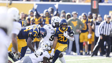 Nov 8, 2025; Morgantown, West Virginia, USA; West Virginia Mountaineers running back Diore Hubbard (20) runs the ball as he’s tackled by Colorado Buffaloes linebacker Jeremiah Brown (42) and Colorado Buffaloes defensive lineman Jehiem Oatis (96) during the first quarter at Milan Puskar Stadium. Mandatory Credit: Ben Queen-Imagn Images