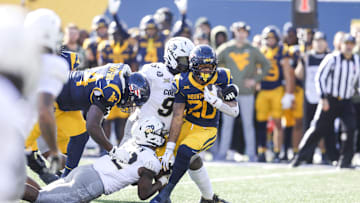 Nov 8, 2025; Morgantown, West Virginia, USA; West Virginia Mountaineers running back Diore Hubbard (20) runs the ball as he’s tackled by Colorado Buffaloes linebacker Jeremiah Brown (42) and Colorado Buffaloes defensive lineman Jehiem Oatis (96) during the first quarter at Milan Puskar Stadium. Mandatory Credit: Ben Queen-Imagn Images