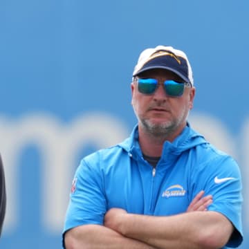 May 12, 2025; El Segundo, CA, USA; Los Angeles Chargers coach Jim Harbaugh (left) and general manager Joe Hortiz watch as quarterback Justin Herbert takes the snap during offseason workouts at The Bolt. Mandatory Credit: Kirby Lee-Imagn Images