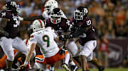Sep 17, 2022; College Station, Texas, USA; Miami Hurricanes quarterback Tyler Van Dyke (9) js hit by Texas A&M Aggies linebacker Chris Russell Jr. (24) and linebacker Tarian Lee Jr. (23) during the second quarter at Kyle Field. Mandatory Credit: Jerome Miron-Imagn Images