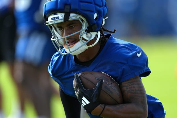 Football player Josh Downs runs in practice in a blue jersey.