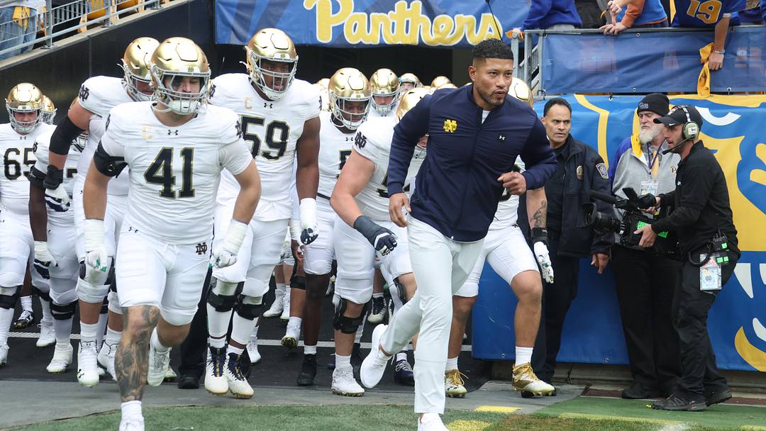 Nov 15, 2025; Pittsburgh, Pennsylvania, USA; Notre Dame Fighting Irish head coach Marcus Freeman (right) leads the team onto the field to play the Pittsburgh Panthers at Acrisure Stadium. Mandatory Credit: Charles LeClaire-Imagn Images Nov 15, 2025; Pittsburgh, Pennsylvania, USA; Notre Dame Fighting Irish head coach Marcus Freeman (right) leads the team onto the field to play the Pittsburgh Panthers at Acrisure Stadium. Mandatory Credit: Charles LeClaire-Imagn Images