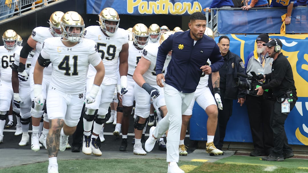 Nov 15, 2025; Pittsburgh, Pennsylvania, USA; Notre Dame Fighting Irish head coach Marcus Freeman (right) leads the team onto the field to play the Pittsburgh Panthers at Acrisure Stadium. Mandatory Credit: Charles LeClaire-Imagn Images Nov 15, 2025; Pittsburgh, Pennsylvania, USA; Notre Dame Fighting Irish head coach Marcus Freeman (right) leads the team onto the field to play the Pittsburgh Panthers at Acrisure Stadium. Mandatory Credit: Charles LeClaire-Imagn Images