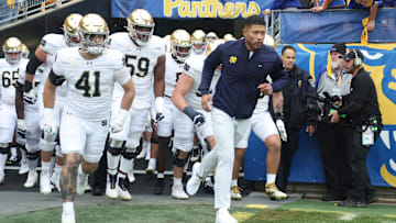 Nov 15, 2025; Pittsburgh, Pennsylvania, USA;  Notre Dame Fighting Irish head coach Marcus Freeman (right) leads the team onto the field to play the Pittsburgh Panthers at Acrisure Stadium. Mandatory Credit: Charles LeClaire-Imagn Images