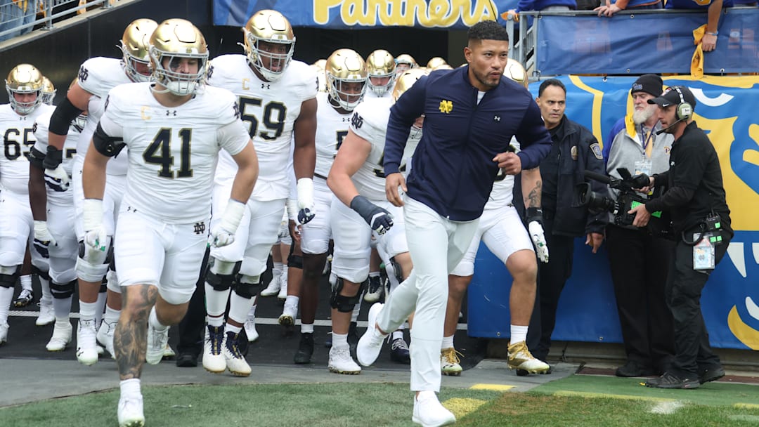 Nov 15, 2025; Pittsburgh, Pennsylvania, USA; Notre Dame Fighting Irish head coach Marcus Freeman (right) leads the team onto the field to play the Pittsburgh Panthers at Acrisure Stadium. Mandatory Credit: Charles LeClaire-Imagn Images Nov 15, 2025; Pittsburgh, Pennsylvania, USA; Notre Dame Fighting Irish head coach Marcus Freeman (right) leads the team onto the field to play the Pittsburgh Panthers at Acrisure Stadium. Mandatory Credit: Charles LeClaire-Imagn Images