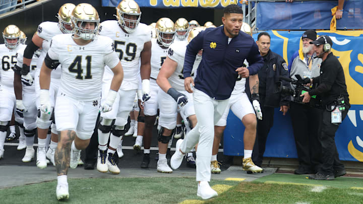 Nov 15, 2025; Pittsburgh, Pennsylvania, USA;  Notre Dame Fighting Irish head coach Marcus Freeman (right) leads the team onto the field to play the Pittsburgh Panthers at Acrisure Stadium. Mandatory Credit: Charles LeClaire-Imagn Images