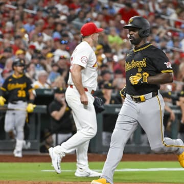 Jun 11, 2024; St. Louis, Missouri, USA;  Pittsburgh Pirates designated hitter Andrew McCutchen (22) runs past St. Louis Cardinals catcher Pedro Pages (43) and relief pitcher Ryan Helsley (56) to score on a sacrifice fly during the ninth inning at Busch Stadium.