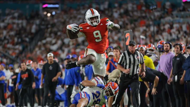 Sep 20, 2025; Miami Gardens, Florida, USA; Miami Hurricanes tight end Elija Lofton (9) hurdles over Florida Gators defensive back Devin Moore (28) during the second quarter at Hard Rock Stadium. Mandatory Credit: Sam Navarro-Imagn Images