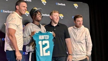 Jacksonville Jaguars first-round draft pick Travis Hunter (with uniform No. 12) poses with team management after his first news conference on April 25 at the Miller Electric Center. From the left are team executive vice-president for football operations Tony Boselli, hunter, coach Liam Coen and general manager James Gladstone.