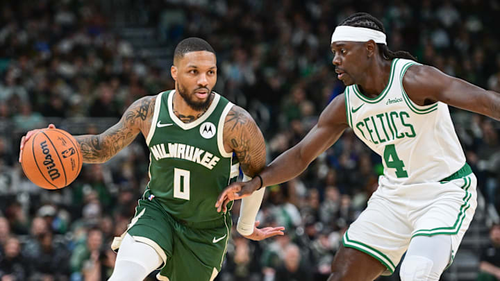 Former Milwaukee Bucks guard Damian Lillard (0) drives for the basket against former Boston Celtics guard Jrue Holiday.
