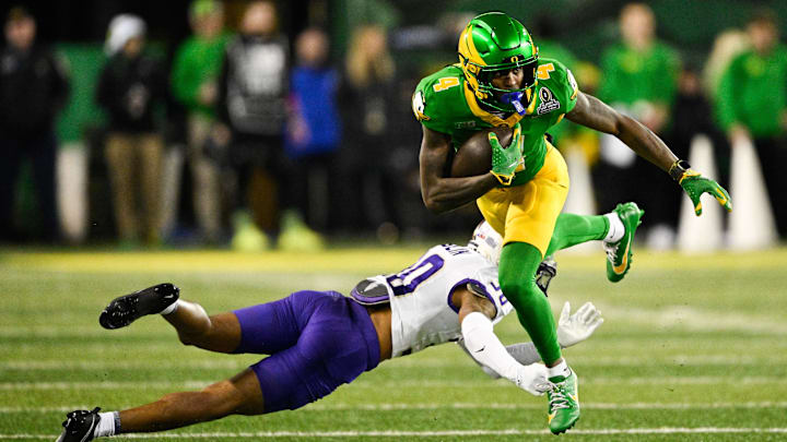 Dec 20, 2025; Eugene, OR, USA;  Oregon Ducks wide receiver Malik Benson (4) breaks a tackle from James Madison Dukes defensive lineman Immanuel Bush (0) during the fourth quarter at Autzen Stadium. Mandatory Credit: Troy Wayrynen-Imagn Images