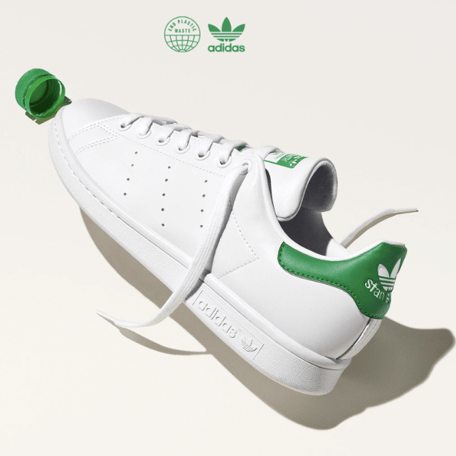 Side view of white and green adidas tennis shoes.