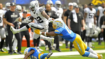 Sep 8, 2024; Inglewood, California, USA; Las Vegas Raiders running back Alexander Mattison (22) gets past Los Angeles Chargers linebacker Daiyan Henley (0) and hurdles over cornerback Asante Samuel Jr. (26) as he runs for a touchdown in the first half at SoFi Stadium. Mandatory Credit: Jayne Kamin-Oncea-Imagn Images