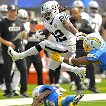 Sep 8, 2024; Inglewood, California, USA; Las Vegas Raiders running back Alexander Mattison (22) gets past Los Angeles Chargers linebacker Daiyan Henley (0) and hurdles over cornerback Asante Samuel Jr. (26) as he runs for a touchdown in the first half at SoFi Stadium. Mandatory Credit: Jayne Kamin-Oncea-Imagn Images