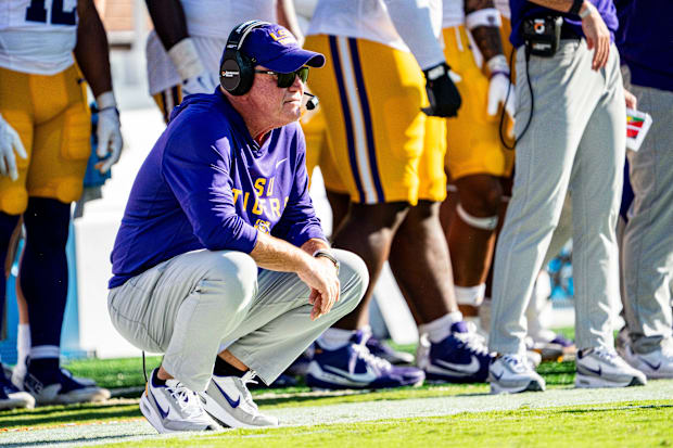 LSU head coach Brian Kelly crouches on the sideline.
