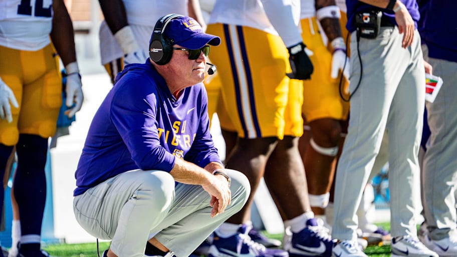 LSU head coach Brian Kelly crouches on the sideline.